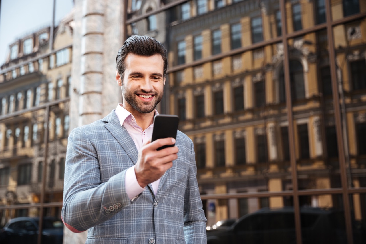 happy handsome man jacket looking mobile phone 2 scaled Large