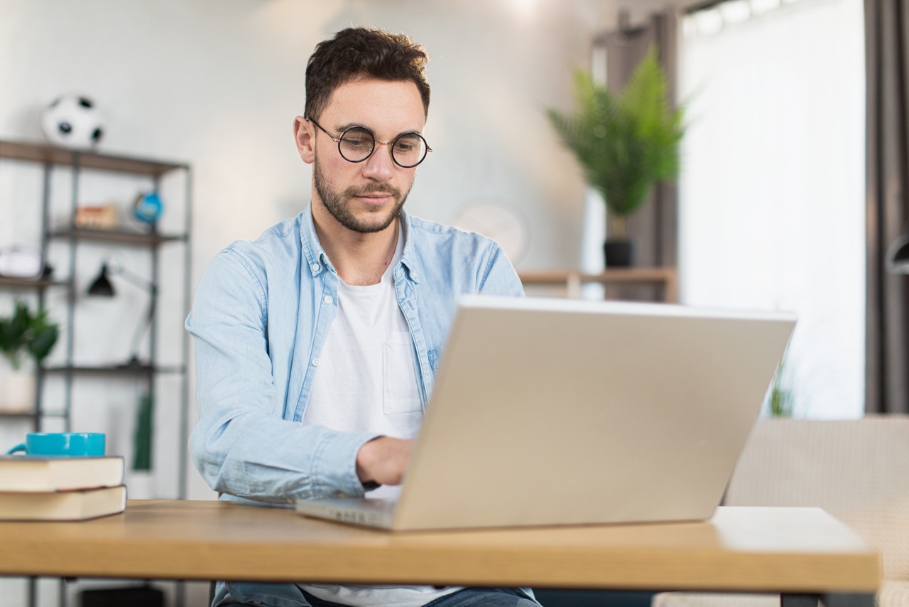 man in eyewear sitting at desk and working on lapt 2022 04 27 03 28 49 utc scaled Large